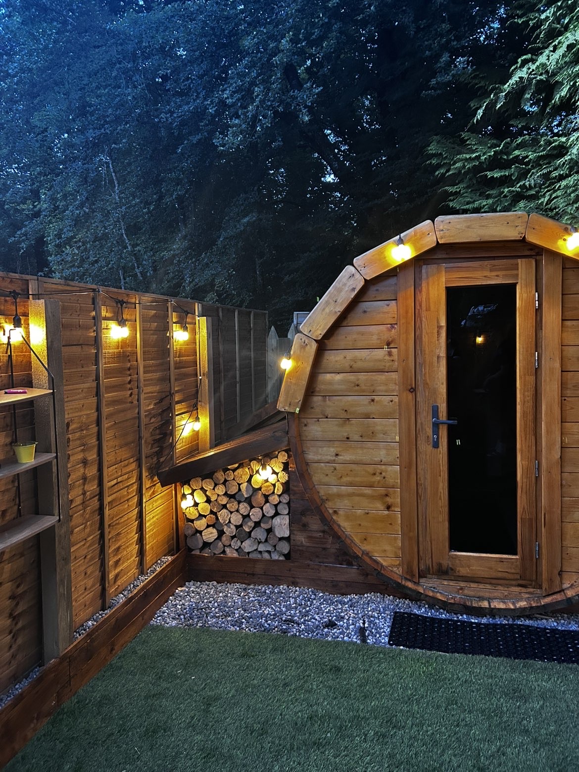 Open door of the An Lasán barrel sauna glowing warmly at night