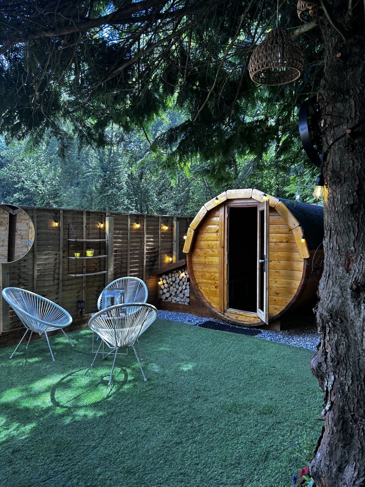 Seating area beside the barrel sauna under string lights